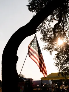 An American flag hanging from an oak tree at golden hour over the Paradise Live food truck area