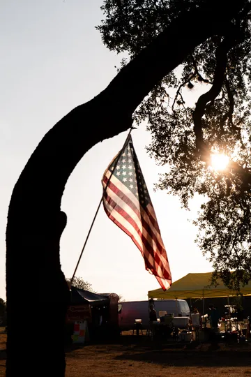 An American flag hanging from an oak tree at golden hour over the Paradise Live food truck area