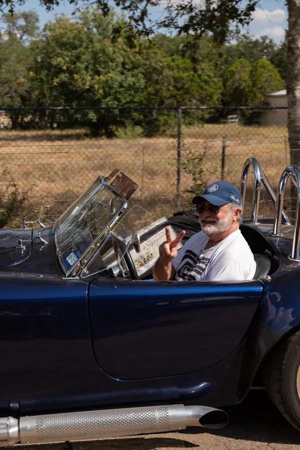 A blue Shelby Cobra replica with its driver waving at the Paradise Live car show