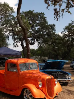A bright orange vintage pickup truck on display at Paradise Live