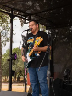 A guitarist singing into a microphone on stage at Paradise Live