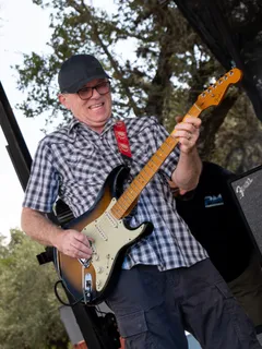A guitarist in a plaid shirt performing on stage at Paradise Live