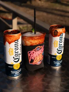 A Paradise Live neon-branded cup beside chili-rimmed Corona cans