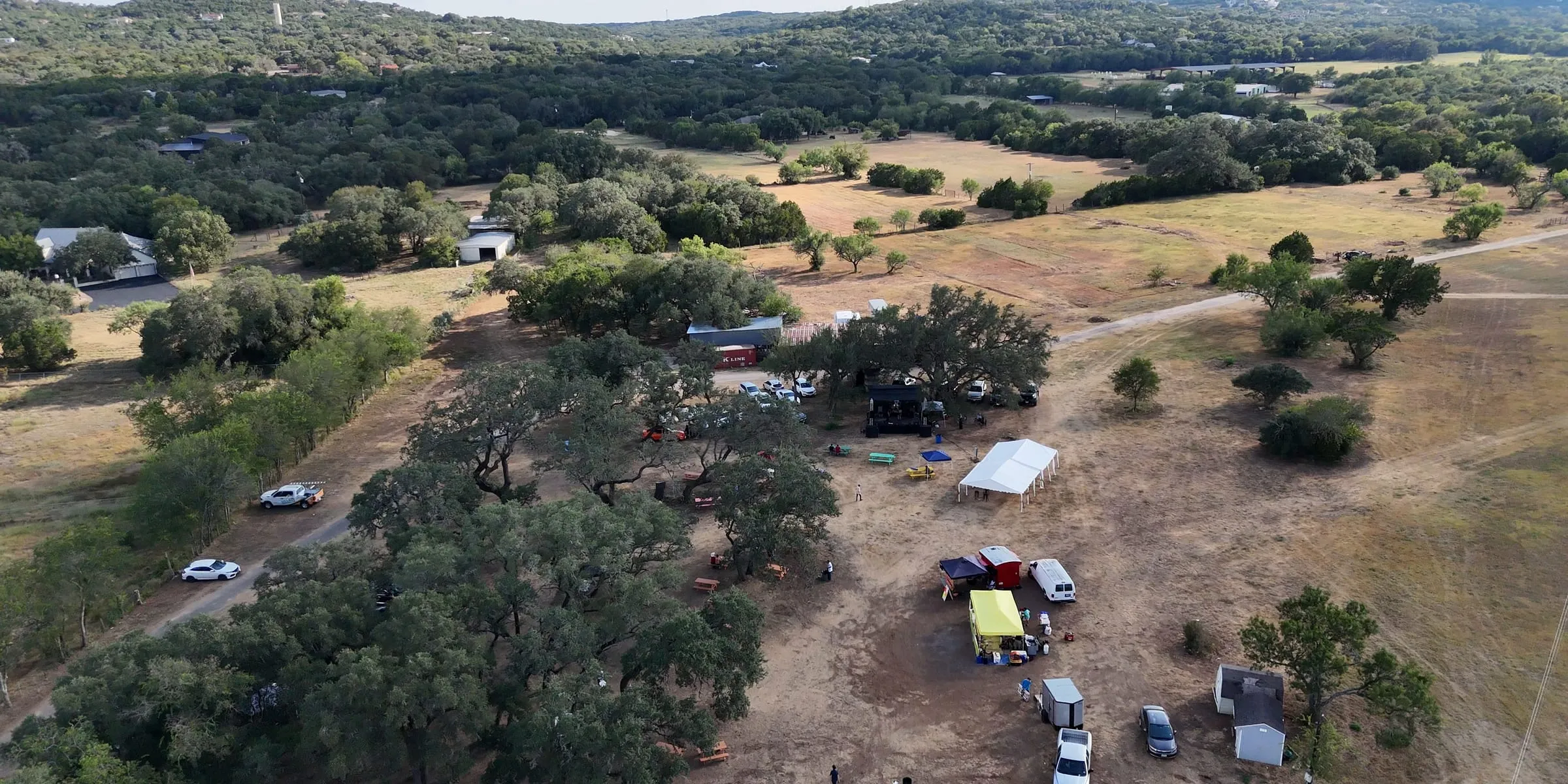 Aerial view of the Paradise Live grounds: open acres, oak trees and event tents in the Texas Hill Country